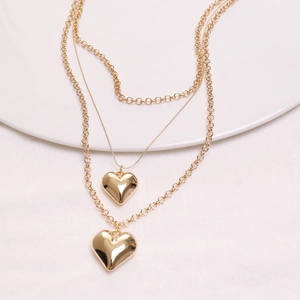 Detail of layered gold heart pendant necklace featuring thick curb and thin snake chains