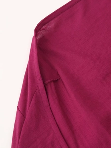 Close-up of deep magenta woven fabric texture and stitching on a halter maxi dress