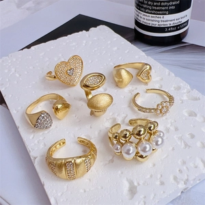 Set of 7 gold 18K plated rings with zircon and pearls on white stone display