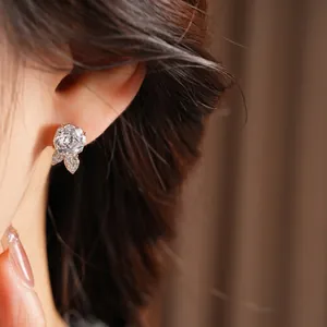 Silver needle stud earrings with zircon leaf and flower design on a female model