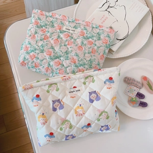 Detail of floral and cartoon quilted cotton cosmetic bags with woven label on a table