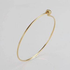 Detail view of a 1.5mm thin gold-plated stainless steel bangle with screwable bead design