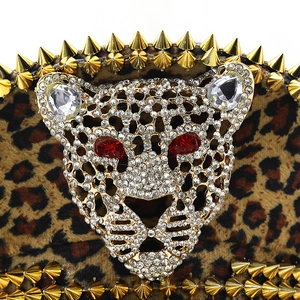 Close-up of leopard print hat featuring a crystal leopard head buckle and gold punk rivets