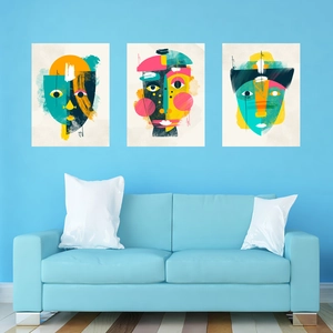 Three-piece set of abstract minimalist face art prints on a blue wall over a sofa