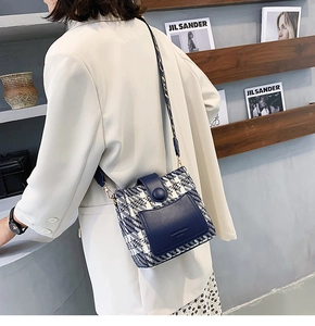 Detail of tweed crossbody bucket bag with blue leather trim and wide woven shoulder strap
