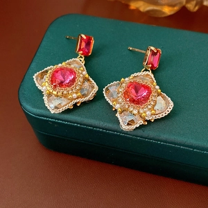 Macro shot of vintage style earrings with red stones and gold plating on green leather