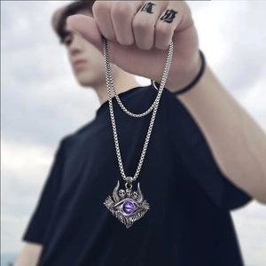 Close-up of vintage silver skull pendant with a purple eye on a metal chain outdoors