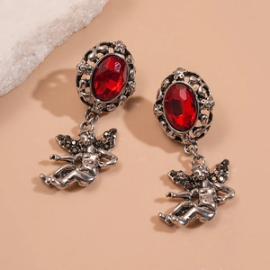 Macro detail of retro drop earrings with red oval gemstone and silver angel pendant