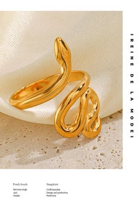 Detailed view of a gold snake-shaped ring on beige silk and stone background
