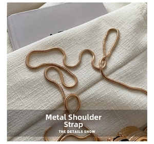 Detail of high-quality gold snake chain strap for fashion bags on textured background