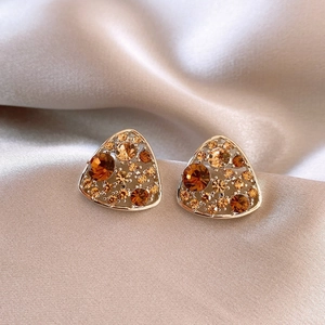 Elegant geometric triangle stud earrings with amber crystals on champagne silk background
