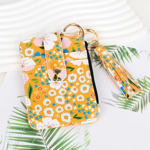Detail view of floral card holder with gold snap button, tassel charm and key ring