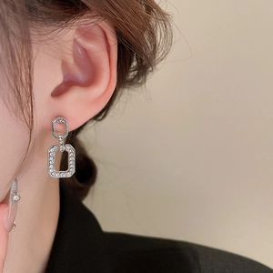 Close-up of interlocking silver geometric earrings with sparkling pavé crystals