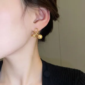 Minimalist matte gold twist stud earrings featuring unique double ball cross design