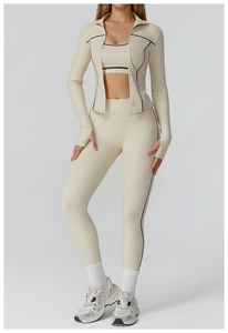 Detail of cream yoga set showing zipper jacket thumbholes and black contrast piping trim