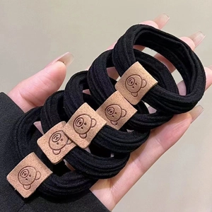 Nahaufnahme von 5 schwarzen elastischen Haargummis mit geprägten Bären-Lederpatches