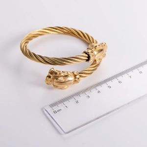 Macro detail of golden dragon head cable bangle with ruler for size reference