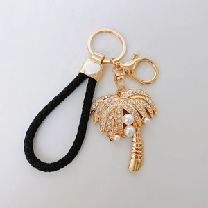 Golden coconut tree keychain with rhinestones, pearls and black braided leather strap