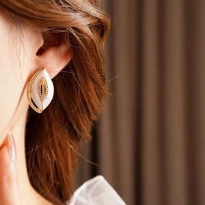 Nahaufnahme von Vintage-Ohrringen in Blattform in Gold und Weiß am Modell