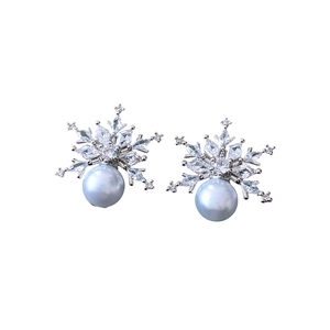 Silver snowflake earrings with sparkling zircons and white pearls on white background
