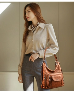 Detail of soft brown leather shoulder bag featuring multiple functional metal zippers