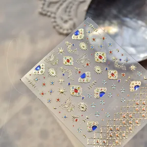 Makroaufnahme goldener Nagelaufkleber mit Sonnen- und Mondmotiven und blauen Edelsteinen