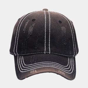 Detailed macro view of washed black cotton baseball cap with white stitching and distressed holes