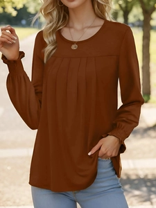 Detail des rostbraunen Langarmshirts mit Faltenmuster auf der Brust und Elastikbündchen