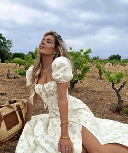 Close-up of a floral summer dress with puff sleeves and a high side slit in a vineyard