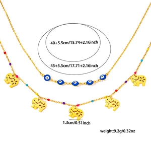 Macro detail of elephant pendant and evil eye beads on double-layer gold chain