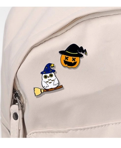 Detail of Halloween enamel pins with wizard owl and pumpkin lantern on canvas bag