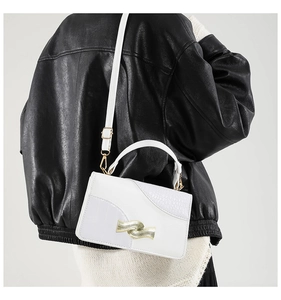 Side view of white crossbody bag with crocodile texture and gold wavy metal buckle
