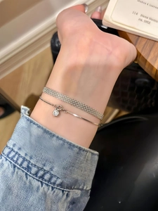 Dettaglio del bracciale a maglia piatta argento e catena snake con piccolo pendente