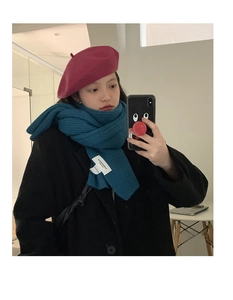 Close-up of thick ribbed knit scarf in teal and burgundy wool beret with black coat