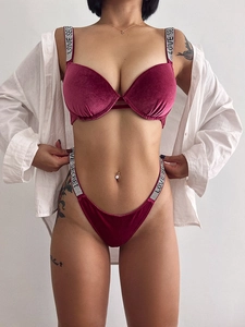 Detail of burgundy velvet lingerie with rhinestone letters on shoulder straps