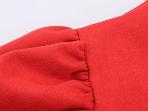 Détail du tissu en daim rouge montrant la texture douce et les plis sur l'épaule