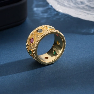 Vintage gold plated wide ring with colorful zircon gemstones on blue background