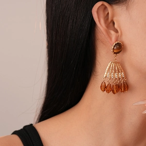 Macro detail of vintage gold earrings with tiger eye beads and crystal tassels on model