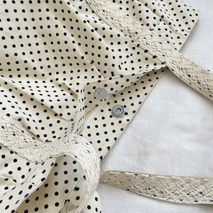 Macro detail of canvas polka dot bag with lace trim and metal snap button closures