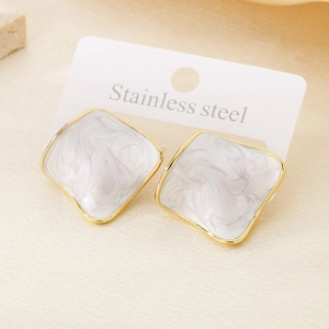 Macro shot of gold stainless steel earrings with white marble square inlay detail