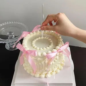 Detailed view of pink ribbon bows on a cream cake with a stylish silver wave candle