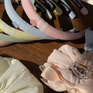 Detail of pastel macaron hair accessories including lace bows and cream clips on wood
