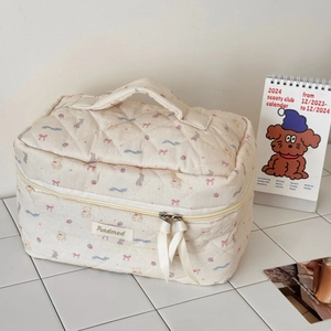 Detail of quilted makeup bag with bear patterns, ribbon zipper and logo label