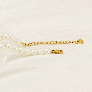 Macro shot of pearl necklace featuring gold lobster clasp and S.Steel engraved tag