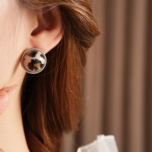 Gros plan d'une boucle d'oreille léopard ronde avec bordure argentée sur un mannequin