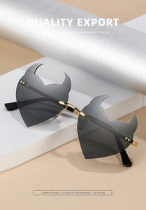 Detail of heart-shaped devil sunglasses with black lenses and gold metal frames