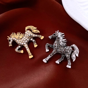 Elegant 18k gold plated horse brooches with white and grey crystals on red velvet