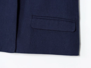 Detailed close-up of dark blue twill fabric texture and pocket flap on the trousers