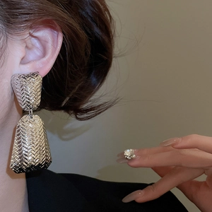 Detail of silver textured hoop earrings with a woven pattern worn by a female model