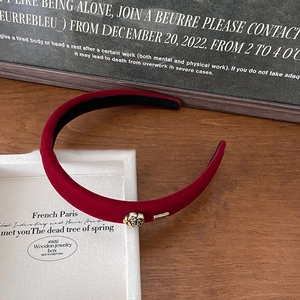 Close-up of velvet dark red headband with elegant golden rose and metallic logo detail